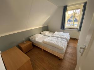 una piccola camera con due letti e una finestra di Camping de Brem a Renesse