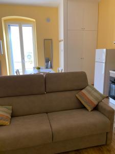 een woonkamer met een bruine bank en een keuken bij casa vacanze HOLIDAY HOME in Trani