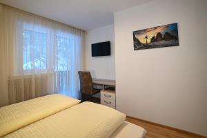 1 dormitorio con cama, escritorio y ventana en Ferienwohnung im Herzen der Dolomiten, en Carezza al Lago