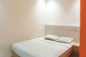 uma cama branca com duas almofadas em cima em TwoSpaces Living at KR Hotel em Palimbão