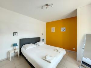 - une chambre avec un lit et un mur jaune dans l'établissement Au Fil De L'Eau - Le Bord de Rance, à Dinan