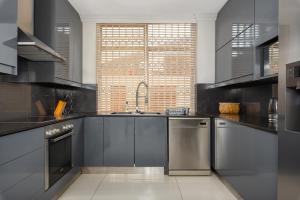 a kitchen with black counters and stainless steel appliances at Sonnekus 5 in Cape Town