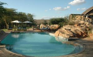 a large swimming pool with rocks in a yard at Maneaters in Tsavo
