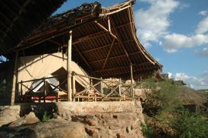 a building with a straw roof on top of a hill at Maneaters in Tsavo