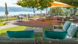 eine Terrasse mit Tischen und Stühlen und Blick auf das Wasser in der Unterkunft Hotel Boldern in Männedorf