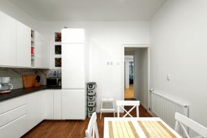 kuchnia z białymi szafkami, stołem i krzesłami w obiekcie Apartament blisko Wawelu w Krakowie