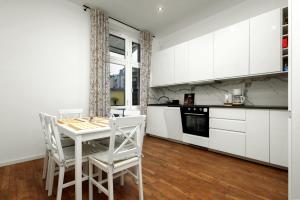 kuchnia z białymi szafkami, stołem i krzesłami w obiekcie Apartament blisko Wawelu w Krakowie