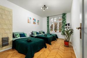 Habitación con 3 camas verdes y ventana. en Apartament blisko Wawelu, en Cracovia
