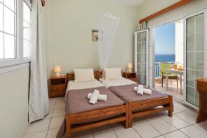 a bedroom with a bed and a balcony with the ocean at Panorama Apartments in Afionas