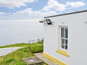 a white building with a window next to the water at St Abbs The Flag House in Saint Abbs