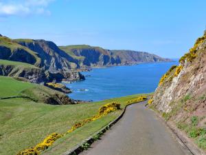 a road on the side of a mountain next to the ocean at St Abbs The Flag House in Saint Abbs