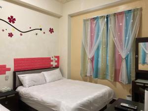 a bedroom with a bed and a window with flowers on the wall at Guanshan Fukuda Homestay in Guanshan