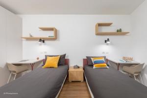 a room with two beds and two tables and chairs at Minerva Guesthouse in Trento
