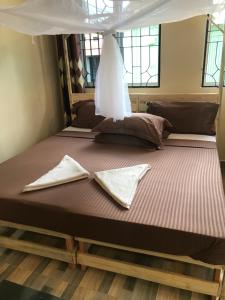 ein großes Bett mit zwei Kissen darauf in einem Zimmer in der Unterkunft L&J Modern Backpackers Kinondoni in Daressalam
