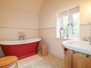 a bathroom with a red bath tub and a sink at Woodland Lodge in Wolverhampton