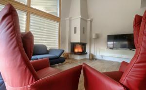 a living room with two red chairs and a fireplace at Holidayhouse4You in Schwanau +18 photos