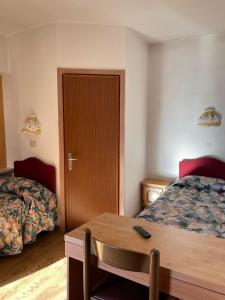 Cette chambre comprend 2 lits et une table en bois. dans l'établissement Garnì Villa Cecilia, à Mazzin