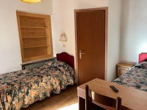 マッツィンにあるGarnì Villa Ceciliaのベッド2台とテーブルが備わるホテルルームです。