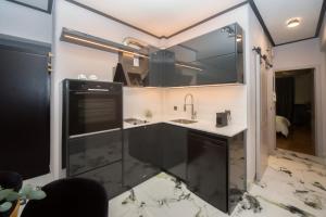 una cocina con armarios negros y fregadero en Luxury Premium Suite #4, en Chalkida