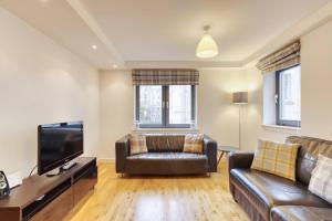 a living room with a couch and a television at *Amazing Location!*In heart of the City. 2BR & Cot in Edinburgh
