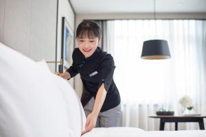 a young boy is making a bed in a room at Xin'an Yihao Hotel - Near Xiamen Railway Station, near Vientiane City, minibar is free in Xiamen