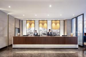 two men sitting at a reception desk in a lobby at Xin'an Yihao Hotel - Near Xiamen Railway Station, near Vientiane City, minibar is free in Xiamen