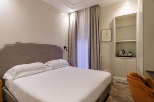 una camera con un letto bianco e una sedia di Hotel Smeraldo a Roma