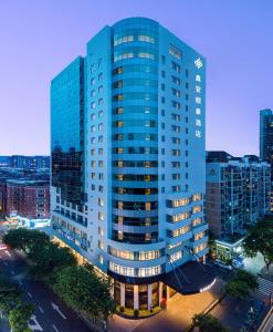 a tall blue building with windows in a city at Xin'an Yihao Hotel - Near Xiamen Railway Station, near Vientiane City, minibar is free in Xiamen