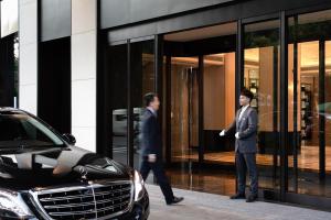 two men walking in front of a building with a car at Xin'an Yihao Hotel - Near Xiamen Railway Station, near Vientiane City, minibar is free in Xiamen