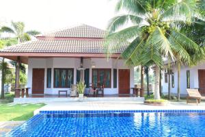 a villa with a swimming pool in front of a house at Waterside Resort in Pran Buri