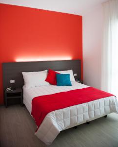 1 dormitorio con 1 cama grande y pared roja en 29 Cav Apartments, en Bollate