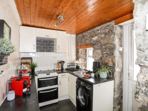 a small kitchen with a stove and a sink at 5 Thomas Street in Llanberis