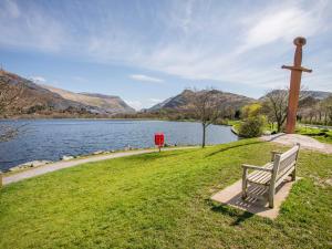 a bench sitting next to a cross next to a lake at 5 Thomas Street in Llanberis