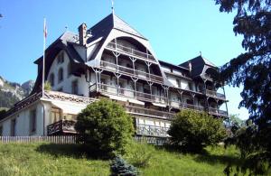 a large white building on top of a hill at Luxury Apartment, Panoramic Mountain Views, 5* Spa Facilities - 4 Bedroom in Chateau-d'Oex