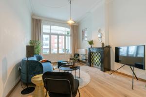 a living room with a blue couch and a tv at Authentic townhouse near the beach of Blankenberge in Blankenberge