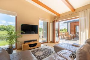 a living room with a couch and a flat screen tv at Dabas Mājas - Your Dream Holiday Spot in Vecslavēkas