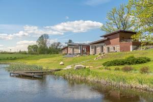 a house on a hill next to a river at Dabas Mājas - Your Dream Holiday Spot in Vecslavēkas