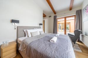 a bedroom with a bed with a chair and a window at Dabas Mājas - Your Dream Holiday Spot in Vecslavēkas