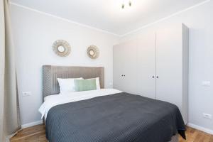 a bedroom with a large bed and white walls at Sunny 2BR Flat - Top Location - Stunning Views in Bucharest
