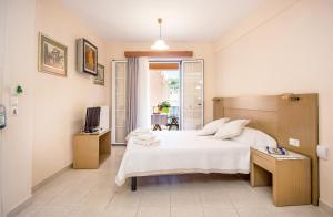 a bedroom with a white bed and a television at Rouchotas Apartments in Argostoli