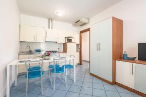 uma cozinha com armários brancos e uma mesa e cadeiras em Bosco Canoro Bibione Resort em Bibione