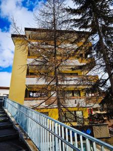 een geel gebouw met een boom ervoor bij FeWo's und Apartment's Schöneck in Davos