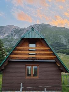 uma cabana de madeira com um telhado de gambrel e uma janela em Mountain house em Žabljak