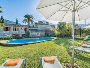 a pool with chairs and an umbrella and a house at Villa Can Fanals by SunVillas Mallorca in Pollença