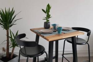 uma mesa de madeira com duas cadeiras, pratos e plantas em Appartement cosy proche la Part Dieu em Lyon