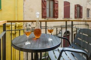 Dois copos de vinho e uma garrafa numa mesa na varanda. em Casa Sorvolou em Chania Town