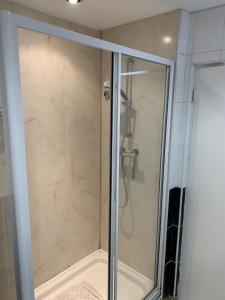 a shower with a glass door in a bathroom at Traeth Rooms in Cardigan