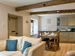 a living room with a couch and a table and a kitchen at Cartwheel Cottage in Hawes