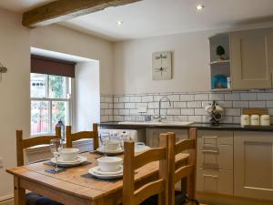 a kitchen with a wooden table with chairs and a sink at Cartwheel Cottage in Hawes