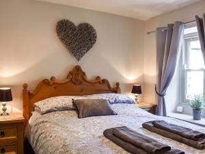 a bedroom with a bed with a heart on the wall at Cartwheel Cottage in Hawes